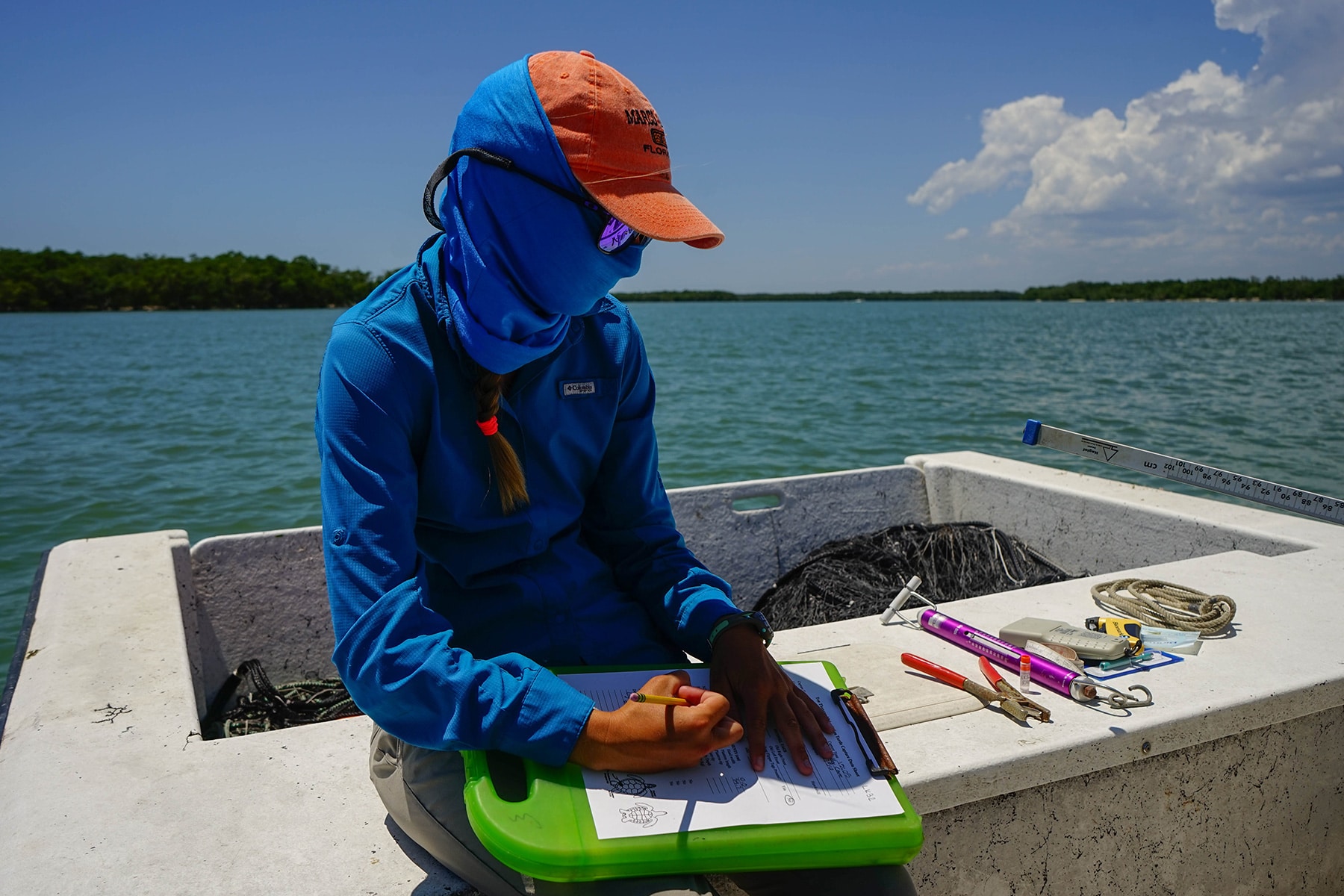 Conservancy of Southwest Florida Science intern sitting on a boat in the Ten Thousand Islands documenting Kemp's ridley turtle information