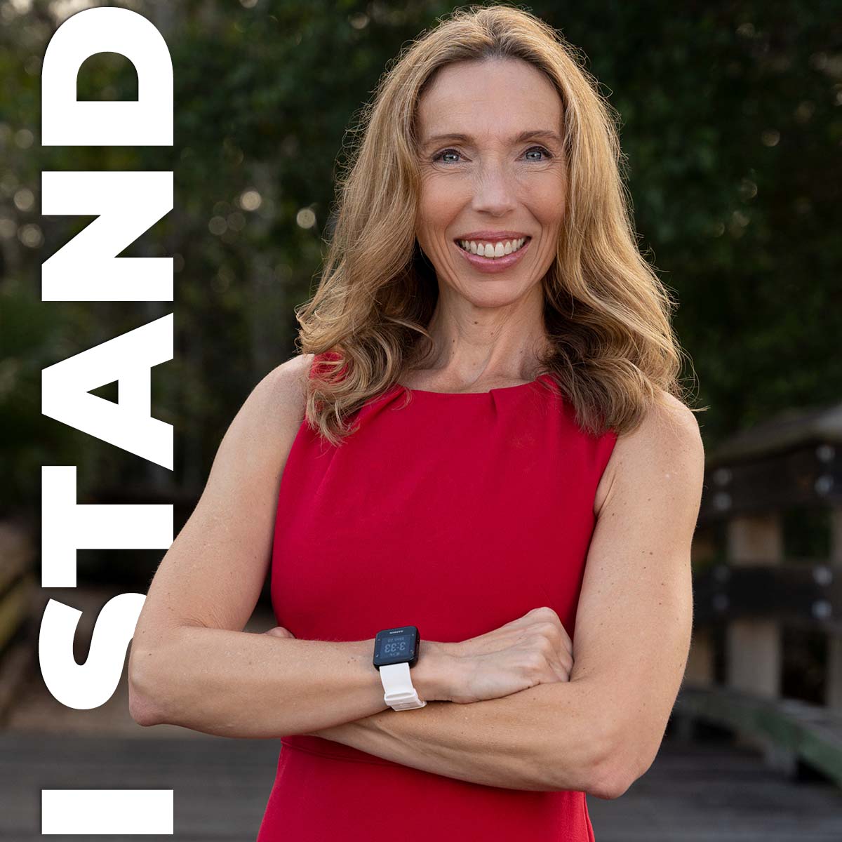 Woman standing with arms folded and the words "I Stand" behind her